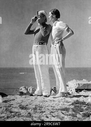 Maine: ca. 1938. Ein Paar steht am Ufer von Maine mit Blick auf den Ozean. Stockfoto