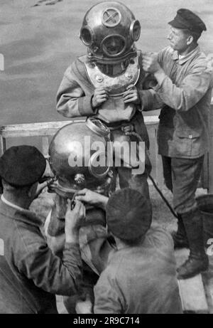 Berlin, Deutschland: c. 1932 Fotograf und Fotojopurnalist Willie Ruge und sein Partner bereiten sich darauf vor, die ersten Unterwasseraufnahmen außerhalb einer Tauchglocke zu machen. Ihre Schuhe wiegen 36 Pfund und die kombinierte Ausrüstung für dieses Abenteuer unter der Oberfläche der Elbe wiegt 320 Pfund. Hier werden die letzten Anpassungen an ihren Tauchanzügen vorgenommen. Stockfoto