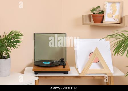 Stilvoller Plattenspieler mit Schallplatte auf Holztisch in gemütlichem Zimmer Stockfoto