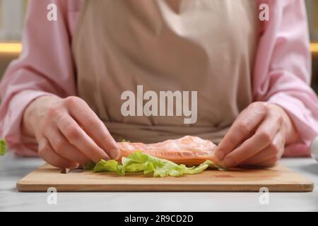 Eine Frau, die leckere Frühlingsrollen am weißen Tisch macht, Nahaufnahme Stockfoto