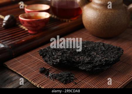 Gebrochener, scheibenförmiger pu-erh-Tee auf einem Holztisch Stockfoto