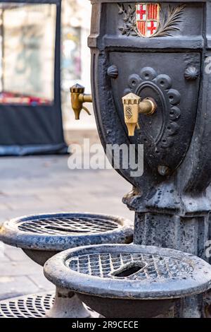 Barcelona, Spanien - 10. FEBRUAR 2022: Öffentlicher gusseiserner Brunnen mit dem Stadtemblem von Barcelona, Spanien. Stockfoto