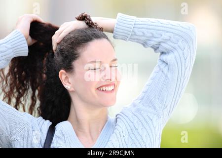 Eine glückliche Frau, die auf der Straße Pferdeschwanz macht Stockfoto