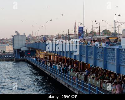 Fshing auf der Galata-Brücke über das Goldene Horn an einem Sommerabend, mit Restaurants auf der Ebene darunter voller Gäste Istanbul, Türkei Stockfoto