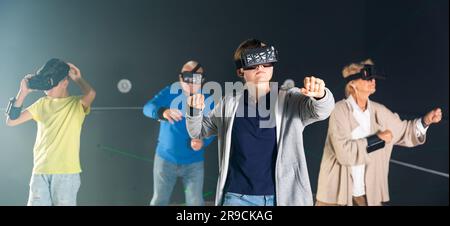 Junge und Mädchen mit ihren Großeltern, die VR-Headsets tragen und Spiele spielen. Stockfoto