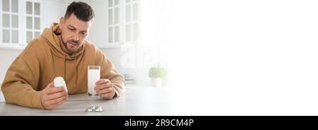 Mann hält ein Glas Medizin für Kater am Tisch in der Küche, Platz für Text. Bannerdesign Stockfoto