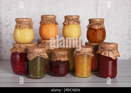 Viele Glasgefäße mit verschiedenen konservierten Produkten auf einem Holztisch Stockfoto