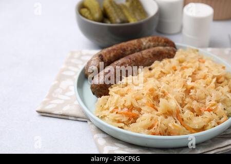 Teller mit Sauerkraut und Würstchen auf hellgrauem Tisch, Nahaufnahme. Platz für Text Stockfoto