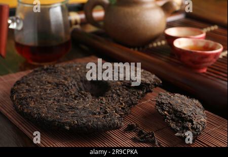 Gebrochener, scheibenförmiger pu-erh-Tee auf einem Holztisch Stockfoto