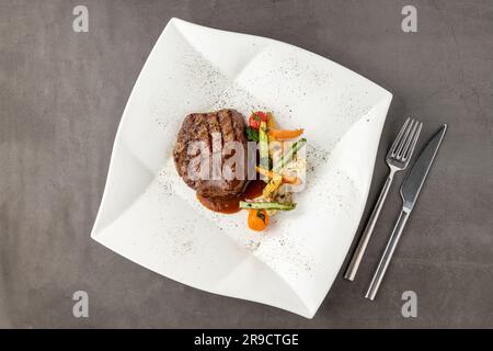 Gegrilltes Rinderfilet mit Demi-Glace-Sauce mit gegrilltem Gemüse auf einem weißen Porzellanteller Stockfoto