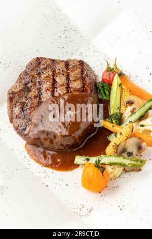 Gegrilltes Rinderfilet mit Demi-Glace-Sauce mit gegrilltem Gemüse auf einem weißen Porzellanteller Stockfoto