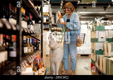 Eine Frau besucht mit ihrem Hund einen Weinladen Stockfoto