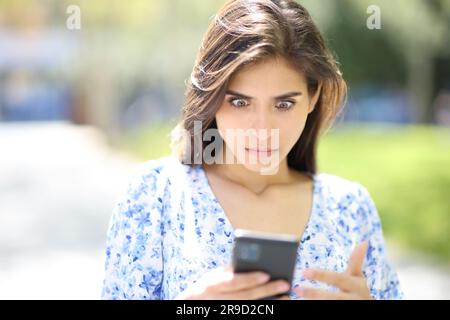 Ein Bild einer perplex Frau, die auf der Straße nach überraschenden Nachrichten telefoniert Stockfoto