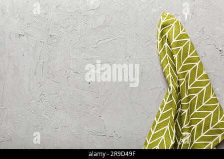 Draufsicht mit grüner Serviette auf Tischhintergrund isoliert. Gefaltetes Tuch für Modell mit Kopierbereich, flach liegend. Minimalistischer Style. Stockfoto