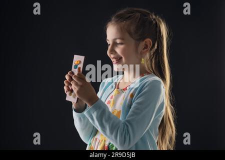 Schokolade und ein ziemlich hungriges Porträt einer kleinen Frau. Ein wunderschönes Mädchen, das Schokoladenriegel essen will. Stockfoto