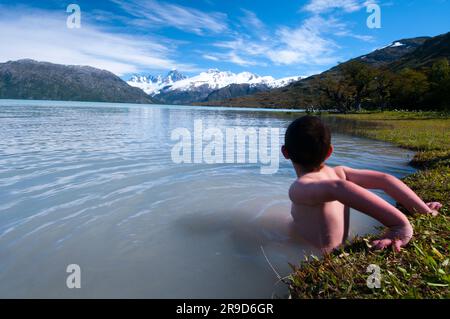 Ein Junge spielt im eisigen Gletscherwasser des Lake O'Higgins, Chile. Stockfoto