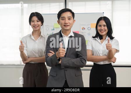 Erfolgreiches Business-Team, das mit einem Kollegen aus dem Firmenbüro im Team lächelt Stockfoto