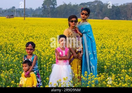 Bangladeschische Jugendliche und Kinder auf dem Lande in einem Senffeld in Singair in Manikganj, Bangladesch. Stockfoto