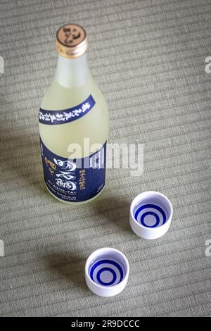 Sake-Becher und -Flasche auf Tatami-Matten, Sake ist ein japanischer Likör aus fermentiertem Reis. Stockfoto