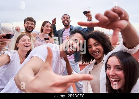 Fröhliches Selfie von Freunden aus gemischten Rassen, die auf einer Party im Freien Geste mit den Fingern machen. Stockfoto