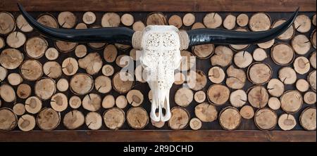 Dekorativ geschnitzter Schädel eines Longhornstiers mit Holzhintergrund Stockfoto