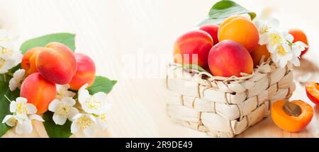 Frische Aprikosen mit Blättern und Blumen in einem Korb auf Holzhintergrund Stockfoto