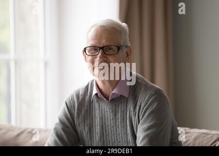 Porträt mit Kopfschuss reifer Mann mit Brille sitzt auf der Couch Stockfoto