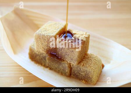 Japanische traditionelle Konfektion namens Warabimochi, die mit Kuromitsu-Sirup übergossen wird Stockfoto