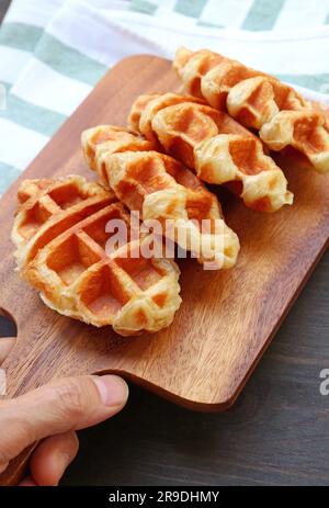 Legen Sie ein Breadboard mit frisch gebackenen Croffles von Hand auf den Küchentisch Stockfoto