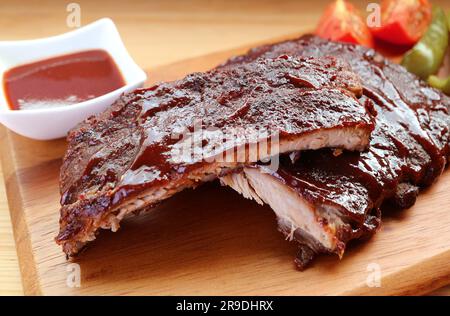 Nahaufnahme köstlicher scharfer Schweinerippchen vom Grill mit gegrilltem Gemüse Stockfoto