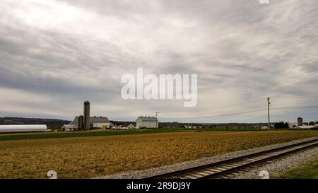 Blick auf eine Amish-Farm mit Scheunen und Silo an einem bewölkten Tag. Stockfoto