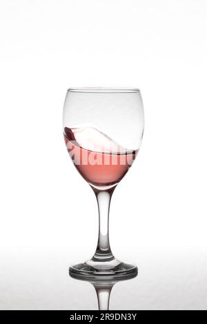 Bewegliches Glas Rosenwein, isoliert auf weißem Hintergrund über einer reflektierenden Oberfläche. Stockfoto