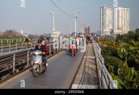 Motorradfahrer überqueren die lange Bien-Brücke über den Red River in Hanoi, Vietnam, von Gia Lam bis ins Stadtzentrum. Stockfoto