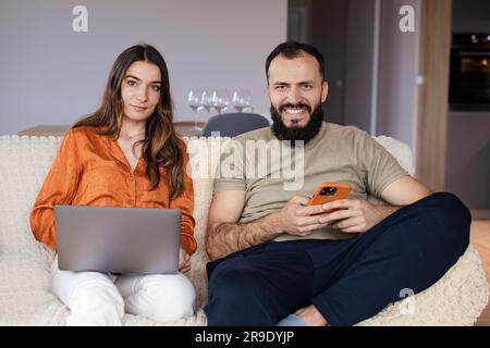 Ein Mädchen und ein Junge, die Geräte benutzen und von zu Hause aus arbeiten Stockfoto