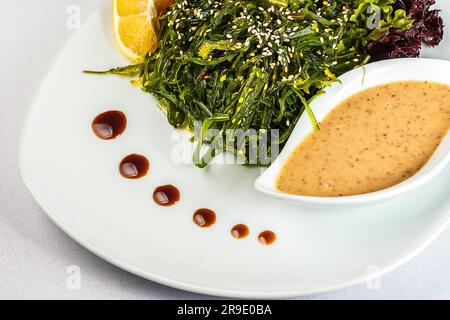 Ein lebendiger Teller mit frischem Gemüse und Seetang, getränkt in eine pikante Zitronensauce und mit Sesamsamen bestreut - die perfekte gesunde Mahlzeit! Stockfoto