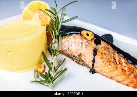 Ein Teller mit frisch gebratenem Lachs, serviert mit einem hausgemachten Kräuter und Schokoladensoße für ein köstliches und dennoch gesundes Meeresfrüchtegericht. Stockfoto