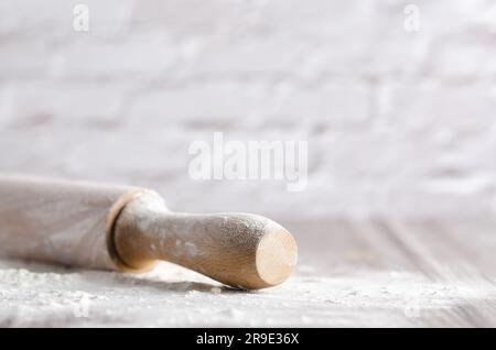 Eine Nudelnadel mit weißem Mehl auf hölzernem Hintergrund mit Kopierraum. Stockfoto