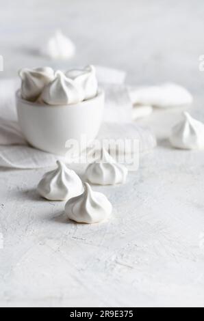 Weiße Meringue-Kekse in einer weißen Schüssel mit einer weißen Serviette, auf weißem Hintergrund. Stockfoto