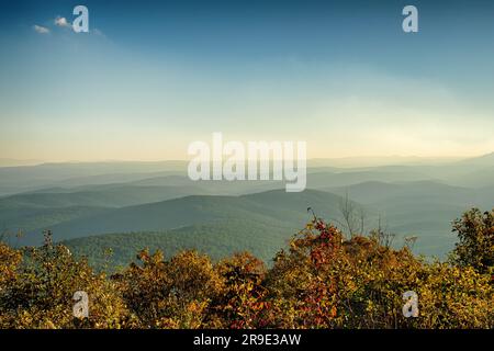 Blick von einem Aussichtspunkt auf die malerische Ouachita-Autobahn am frühen Morgen im November mit Herbstfarben und Nebel über Tälern Stockfoto