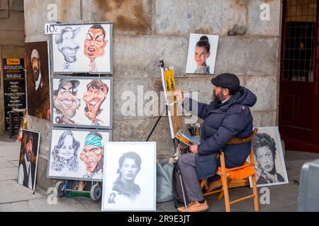 Madrid, Spanien - 16. FEBRUAR 2022: Älterer Straßenkünstler malt und zeichnet Porträts auf der Plaza Mayor in Madrid, Spanien. Stockfoto