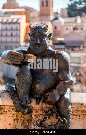 Segovia, Spanien - 18. FEBRUAR 2022: Lustige Skulptur eines Teufels, die ein Selfie gegen das antike römische Aquädukt von Segovia macht, dem wichtigsten Symbol von Segovi Stockfoto