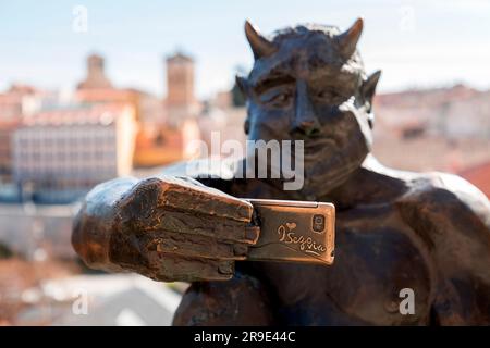 Segovia, Spanien - 18. FEBRUAR 2022: Lustige Skulptur eines Teufels, die ein Selfie gegen das antike römische Aquädukt von Segovia macht, dem wichtigsten Symbol von Segovi Stockfoto