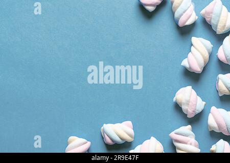 Weiße, gelbe, rosa und hellblaue Marshmallows auf blauem Hintergrund mit Kopierraum. Stockfoto