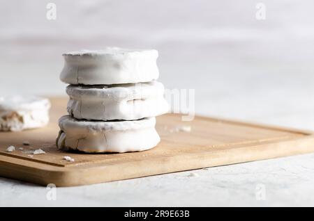 Weiße Alfajores gefüllt mit Dulce de leche auf einem Holzbrett und weißem Hintergrund. Stockfoto