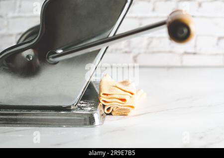 Butternusskürbis-Teig in einer Nudelmaschine auf Marmorhintergrund. Stockfoto