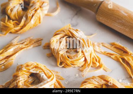 Butternusskürbis-Nudelnester und eine rollende Nadel auf Marmorhintergrund. Stockfoto