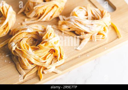 Butternusskürbis-Nudeln nisten auf einem Holzbrett auf Marmorhintergrund. Stockfoto