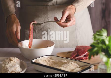 Nahaufnahme von weiblichen Händen, die argentinische Milanesas in der Küche zu Hause kochen. Stockfoto
