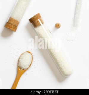 Grobes Salz in Glasbehältern und auf einem Holzlöffel auf weißem Hintergrund. Stockfoto