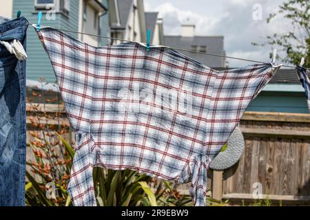 Ein männerhemd, das in einem Garten an einer Wäscheleine hängt Stockfoto